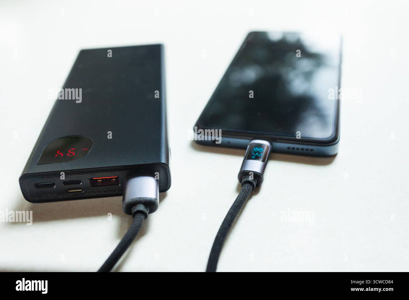 Primo piano della ricarica di uno smartphone da un power Bank tramite cavo USB Foto Stock