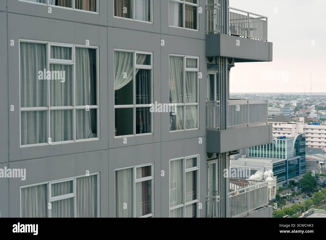 Moderno edificio di appartamenti grigio con finestre multiple e vista sulla città Foto Stock