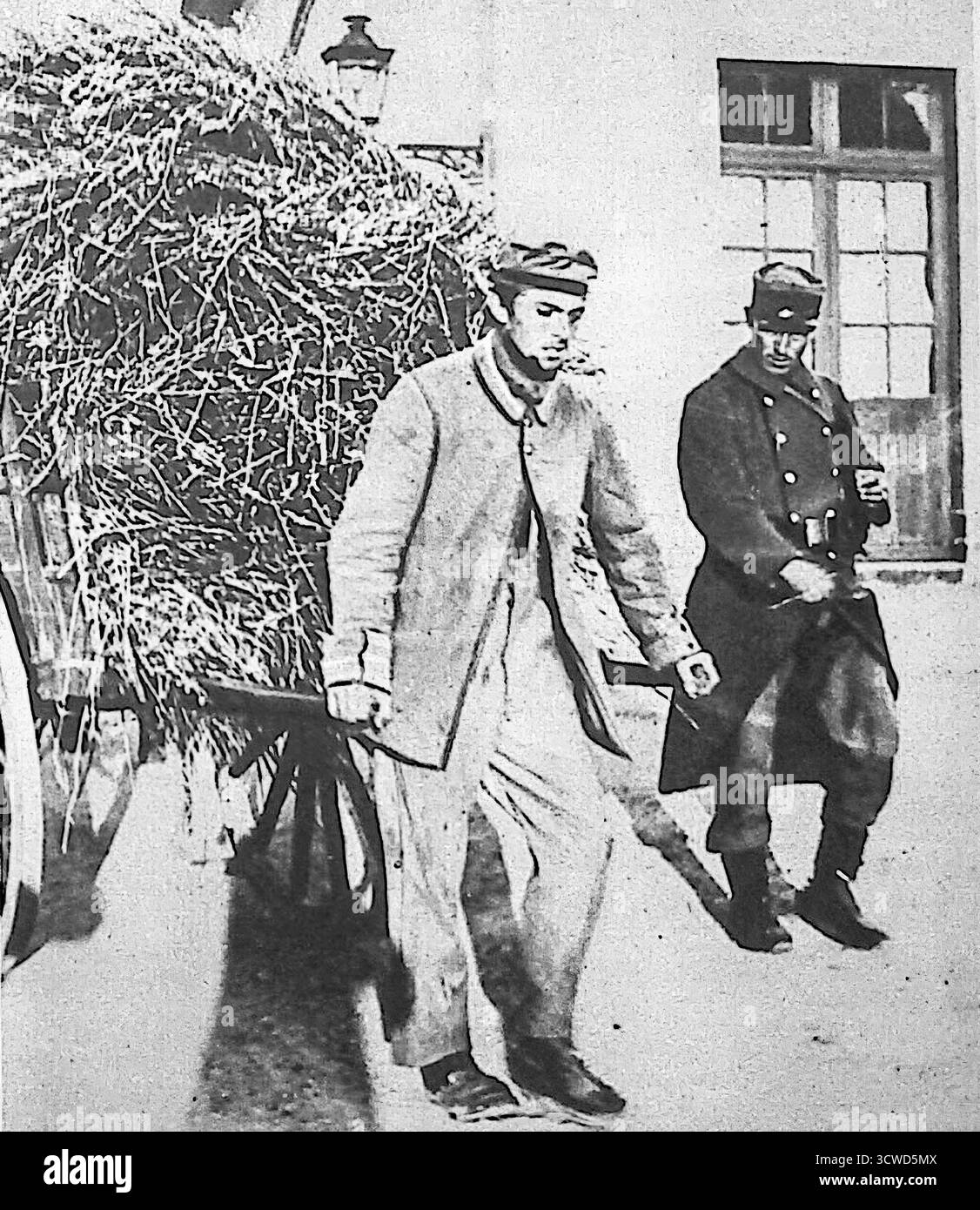 Un'immagine dell'edizione di le Miroir dell'ottobre 1914 mostra un prigioniero di guerra tedesco in Francia che esegue lavori manuali, tirando un pesante carico di fieno mentre guardato dai soldati francesi. I tedeschi catturati erano spesso utilizzati per lavori stradali, attività agricole o compiti militari nei campi. L'immagine in bianco e nero illustra sia l'uso pratico del lavoro POW che il messaggio propagandistico dei soldati nemici posti sotto il controllo francese durante la prima guerra mondiale Foto Stock