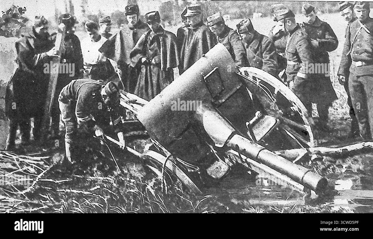 Dal numero di ottobre 1914 di le Miroir, un'immagine in bianco e nero mostra i soldati belgi riuniti intorno a un cannone tedesco da 8 cm abbandonato nella campagna allagata a sud di Anversa. Le forze tedesche, rallentate dalla terra inondata, lasciarono indietro l'artiglieria mentre si ritiravano. La fotografia illustra la strategia difensiva del Belgio di usare l'acqua per bloccare gli avanzamenti, mentre la propaganda alleata celebrava l'umiliazione delle truppe tedesche costrette ad abbandonare armi preziose. Foto Stock