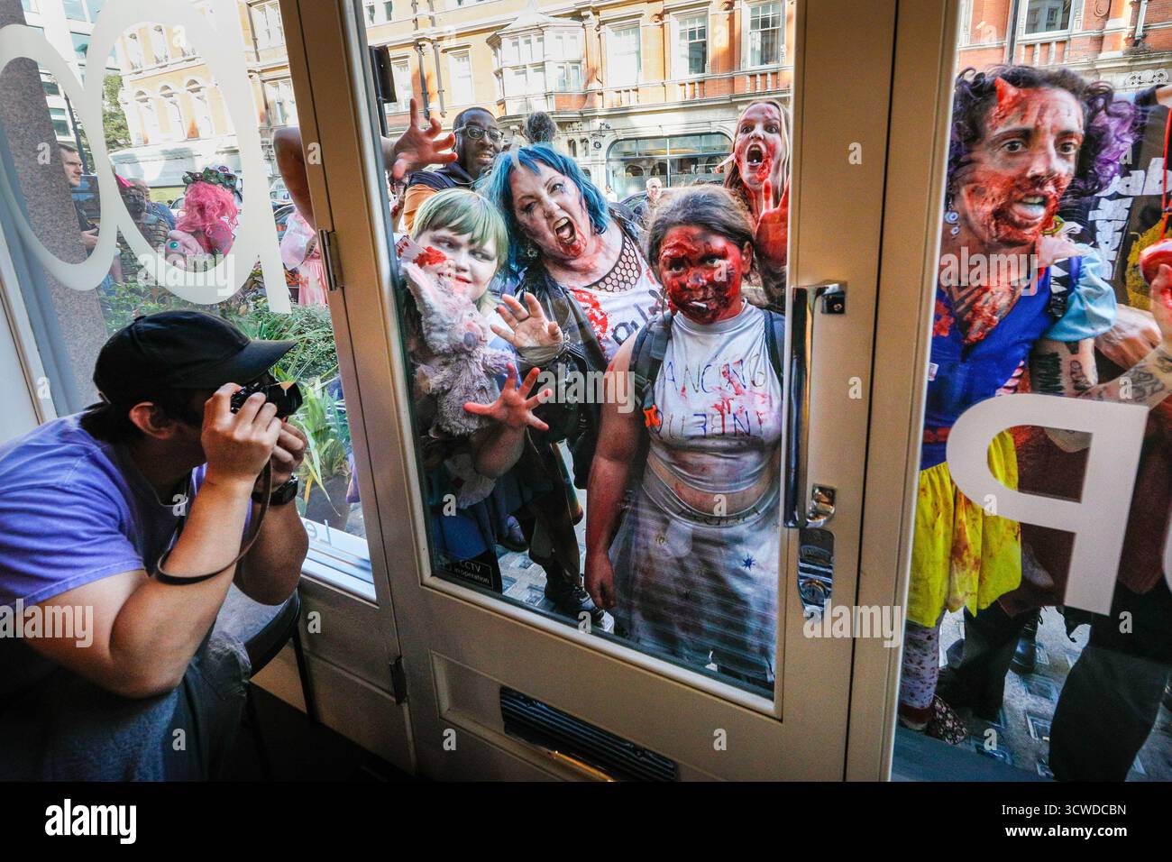Londra, Regno Unito. 11 ottobre 2025. I fotografi all'interno di un negozio di fotocamere Leica sono ansiosi di immortalare l'apocalisse zombie che passa. I partecipanti celebrano l'annuale giornata Mondiale dello Zombie con una passeggiata nel centro di Londra. L'evento è non politico e adatto alle famiglie, con molti fan che si vestono con abiti spaventosi e costumi creativi dell'apocalisse. Crediti: Imageplotter/Alamy Live News Foto Stock