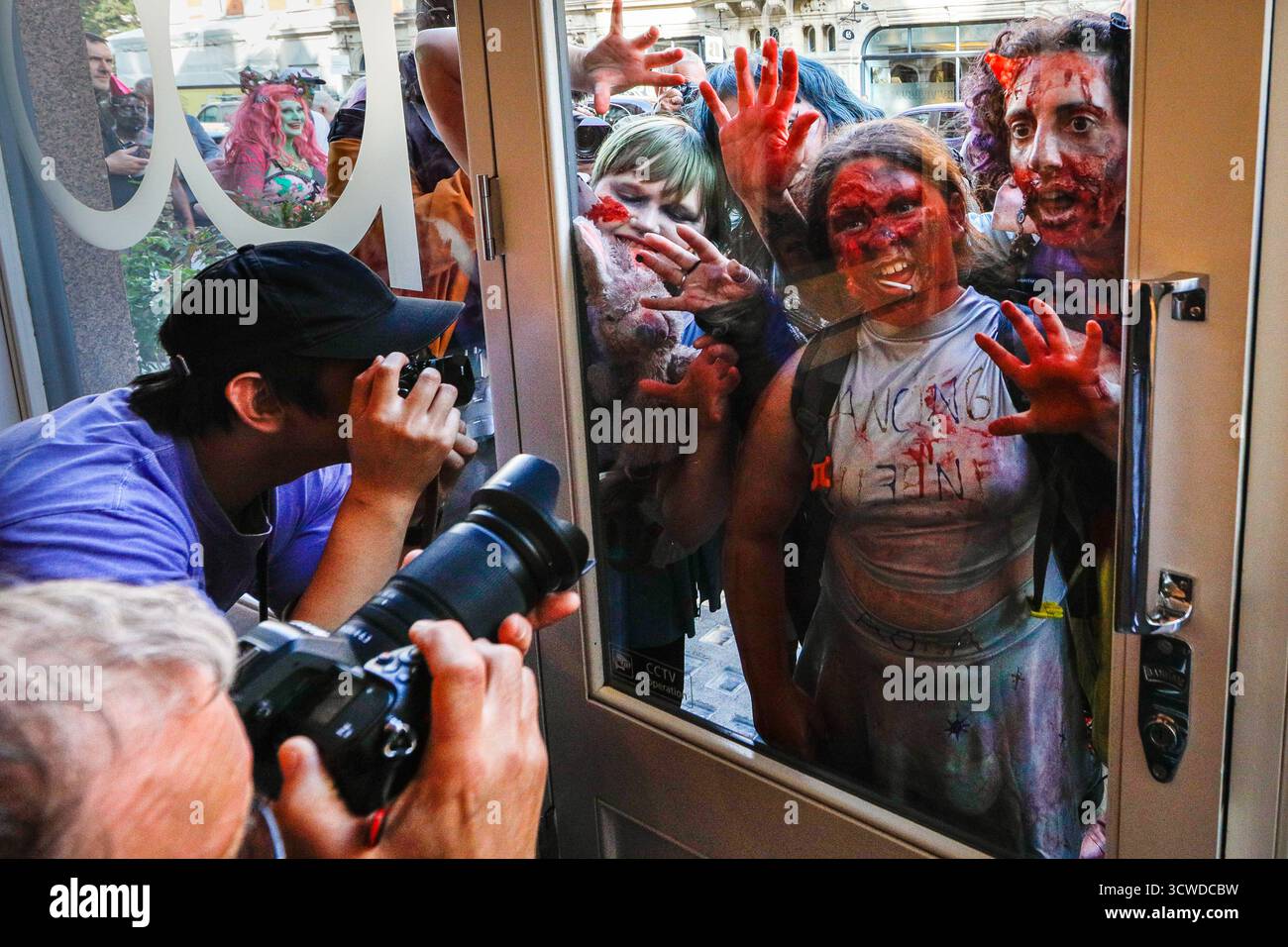 Londra, Regno Unito. 11 ottobre 2025. I fotografi all'interno di un negozio di fotocamere Leica sono ansiosi di immortalare l'apocalisse zombie che passa. I partecipanti celebrano l'annuale giornata Mondiale dello Zombie con una passeggiata nel centro di Londra. L'evento è non politico e adatto alle famiglie, con molti fan che si vestono con abiti spaventosi e costumi creativi dell'apocalisse. Crediti: Imageplotter/Alamy Live News Foto Stock