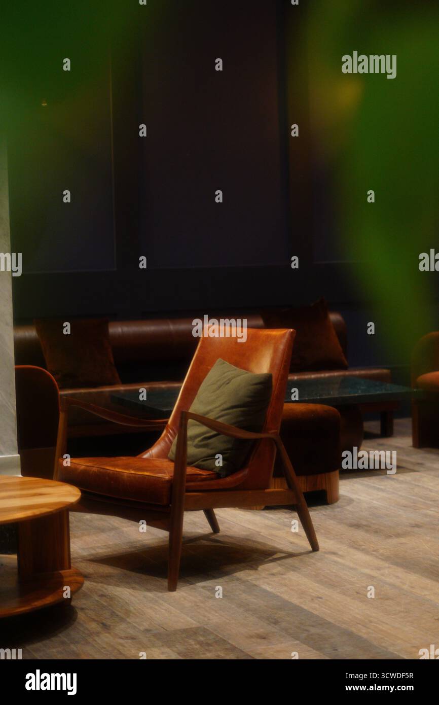 Accogliente angolo salotto con poltrona in pelle della metà del secolo e illuminazione soffusa Foto Stock