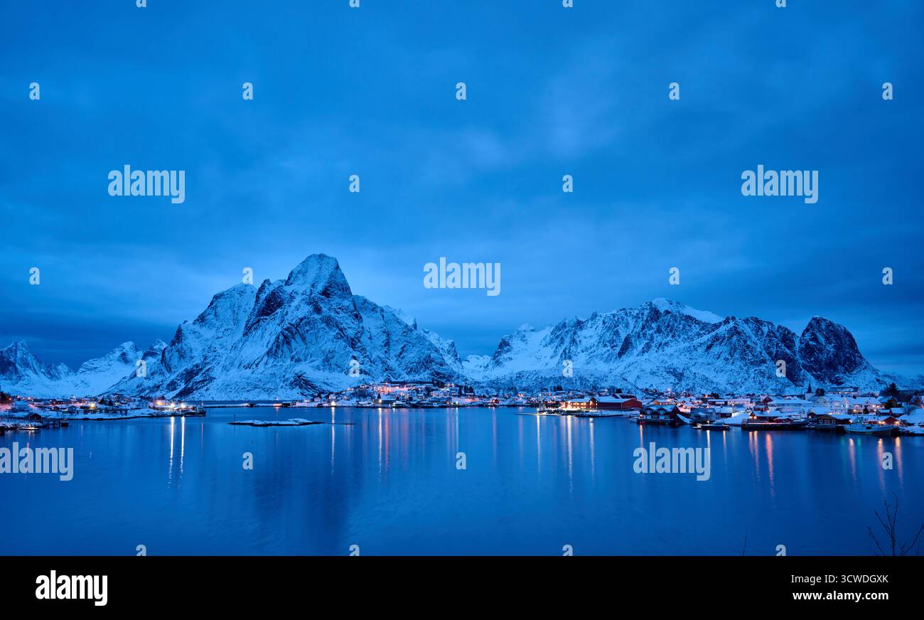Ripresa notturna di Reine illuminata con paesaggi invernali e montagne, Lofoten, Norvegia, Europa Foto Stock