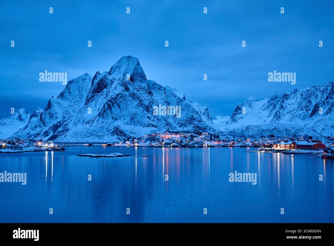 Ripresa notturna di Reine illuminata con paesaggi invernali e montagne, Lofoten, Norvegia, Europa Foto Stock