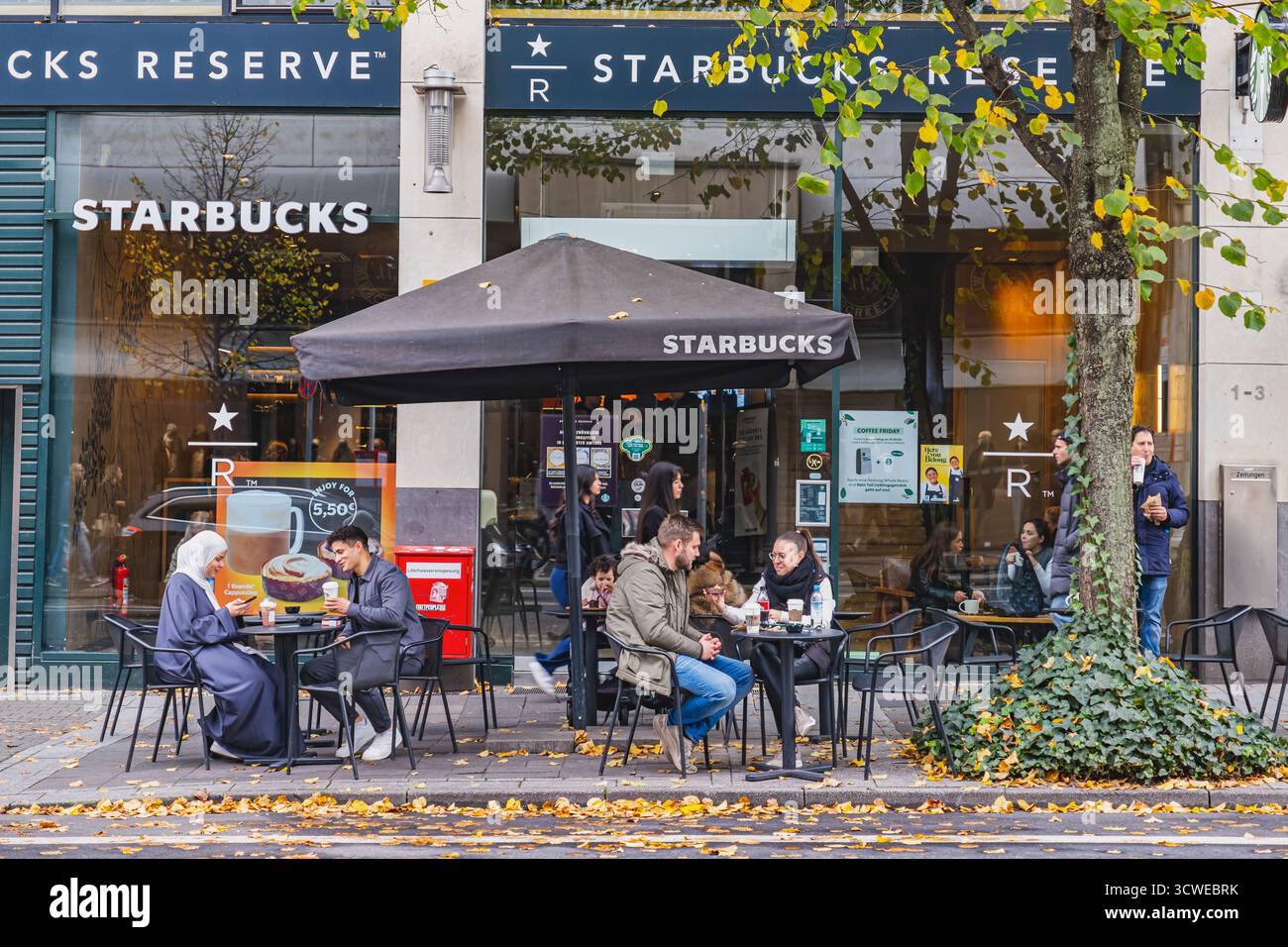 Persone che si godono un drink sedute all'esterno presso la caffetteria Starbucks nel centro della città Foto Stock
