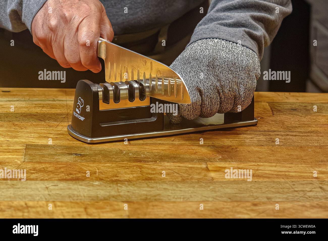 Affilatura accurata dei coltelli in cucina Foto Stock