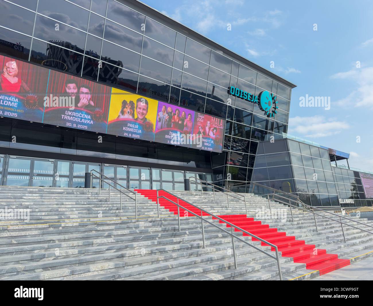 Lubiana, Slovenia – 13.09.2025: Nuovo edificio del cinema Odiseja con ingresso su tappeto rosso e cartelloni digitali sulla facciata Foto Stock