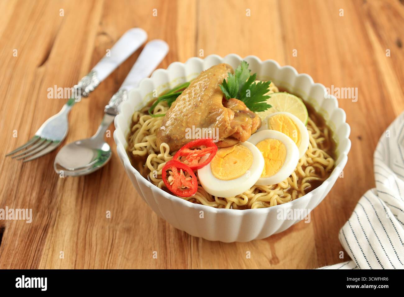Indomie Rebus o Instant Boiled Noodle con Soto Flavour, Instant Noodles indonesiani con uova bollite a fette, pomodoro e ali di pollo Foto Stock
