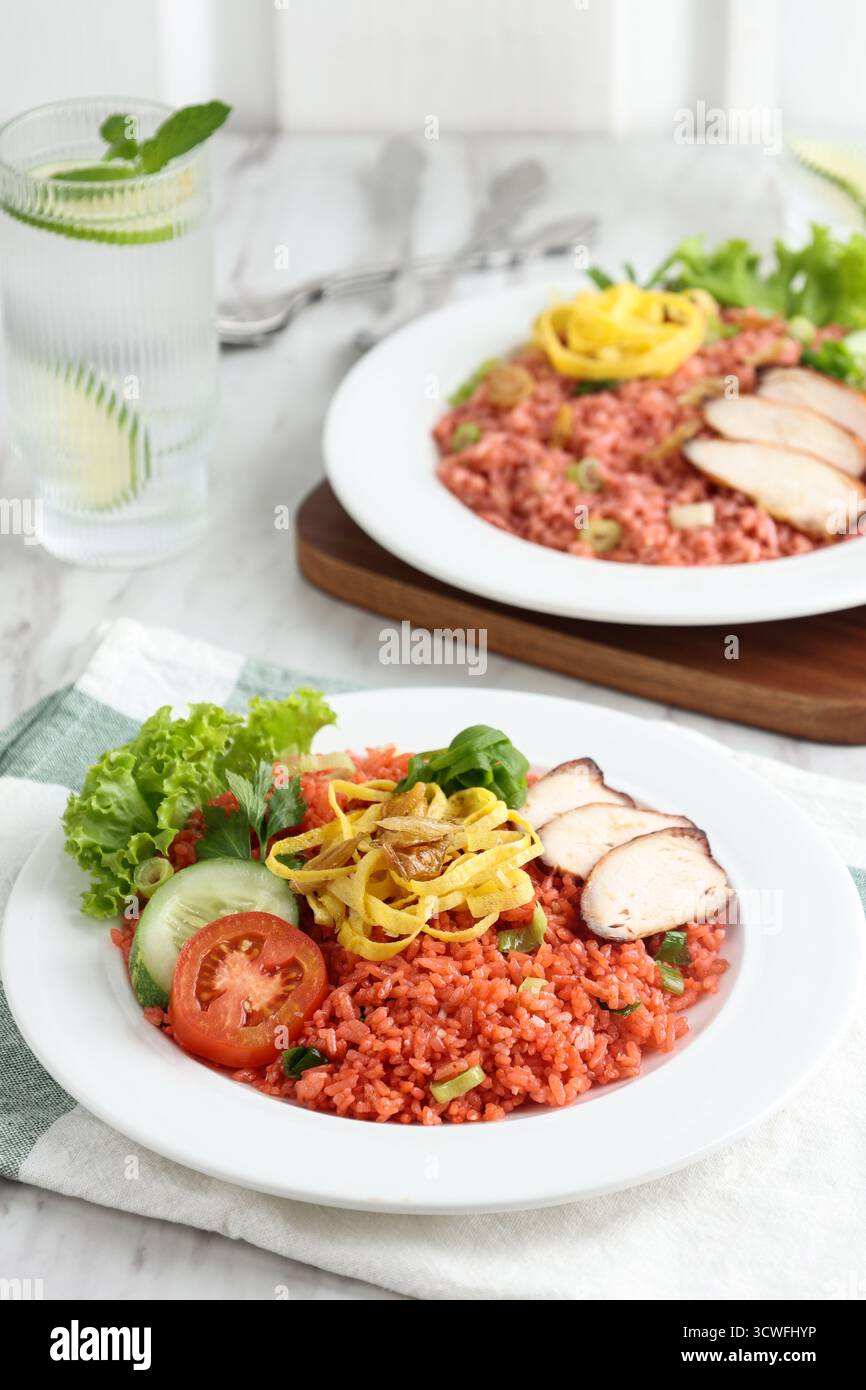 Riso fritto rosso o nasi Goreng Merah con pollo a fette e Telur Dadar Foto Stock