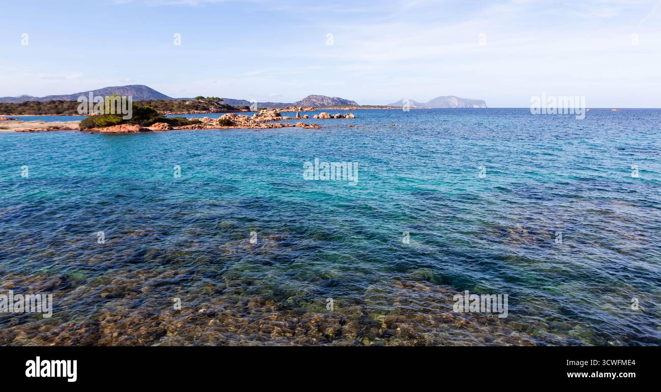 Acque turchesi della costa sarda. Le sfumature color smeraldo del Mediterraneo si fondono con il cielo limpido, creando un tranquillo scenario naturale. Foto Stock