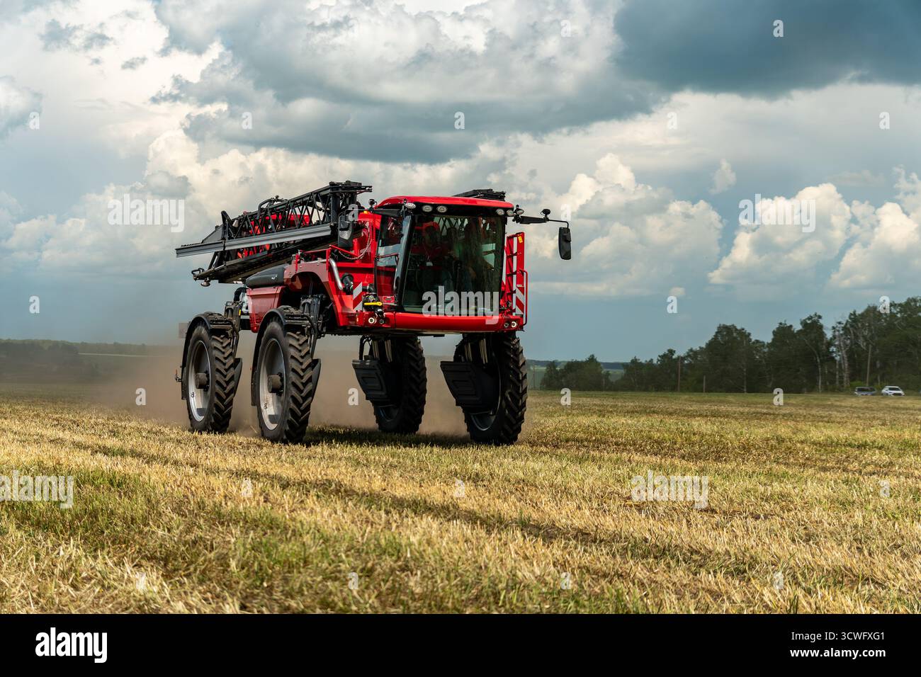 trattori agricoli rossi che coltivano campi sopra il cielo blu. Concetto di raccolta, dissodamento del suolo e delle piante. Foto Stock