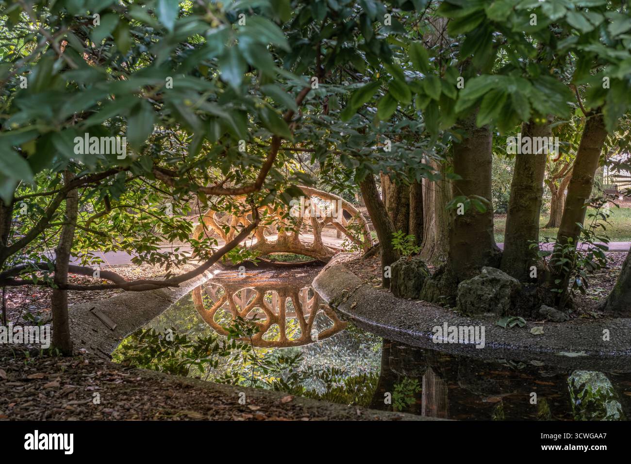 Romantico ponte ornamentale in pietra sullo stagno nel Parco della Florida, Vitoria-Gasteiz, Paesi Baschi, Spagna. Giardino storico con lussureggianti alberi verdi. Ideale per t Foto Stock