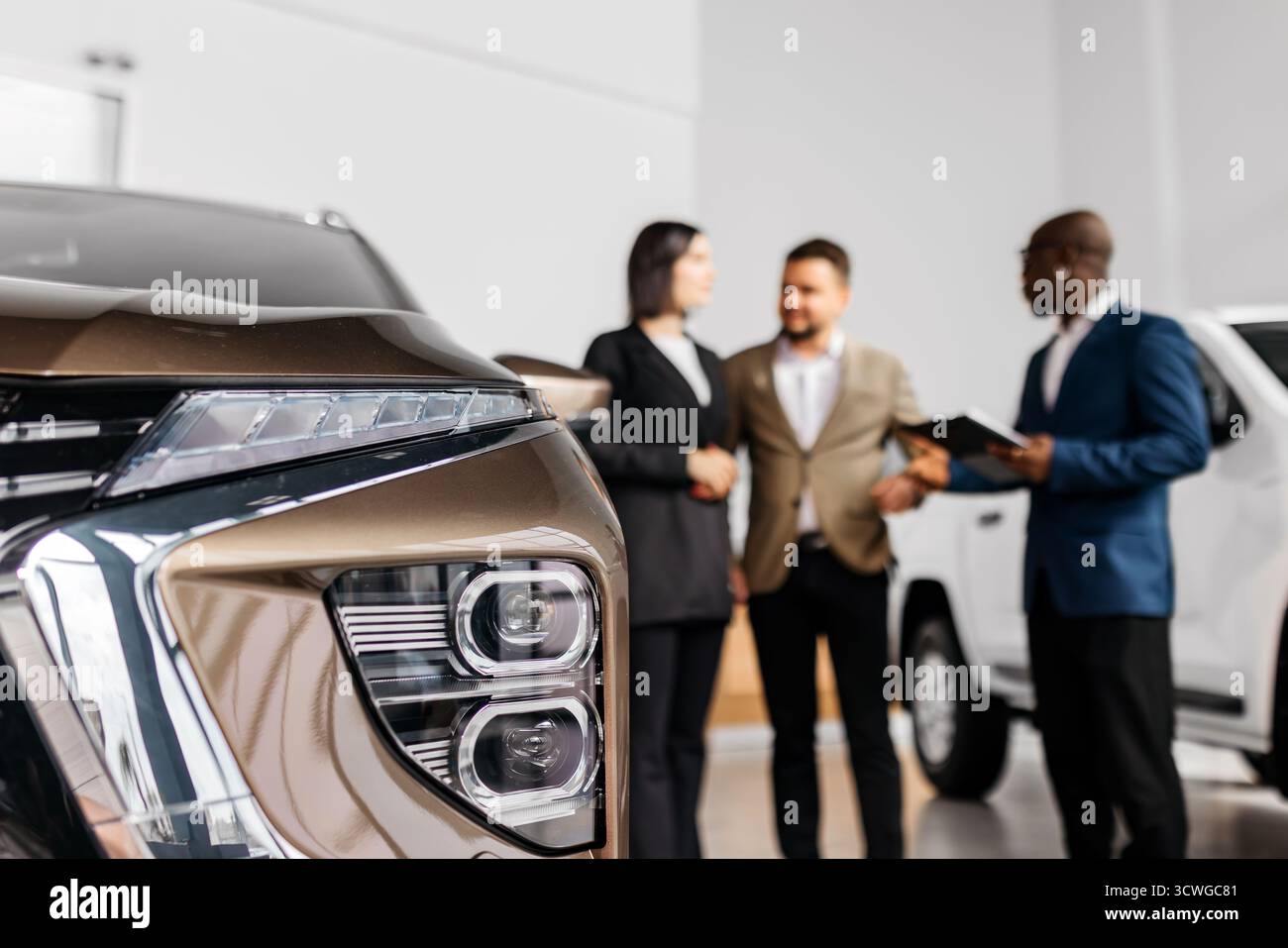 Un rappresentante di vendita di auto professionale si impegna con una coppia in una concessionaria di auto elegante, mettendo in evidenza le caratteristiche del veicolo e fornendo un servizio eccezionale Foto Stock