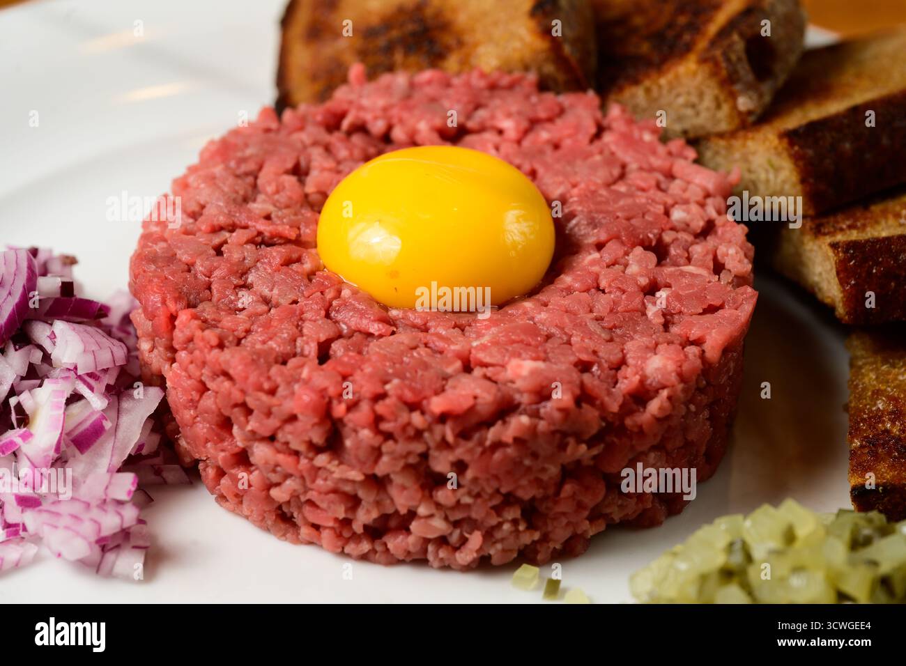 Tartare di manzo Hovezi Tatarak in stile ceco con tuorlo d'uovo crudo, pane tostato Topinki Cipolla rossa e Gherkin Foto Stock