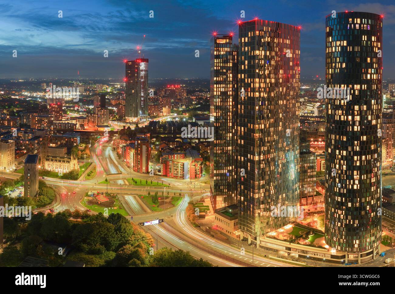 Immagine aerea al crepuscolo dello skyline di Manchester con grattacieli illuminati e la via mancuniana sottostante. Foto Stock