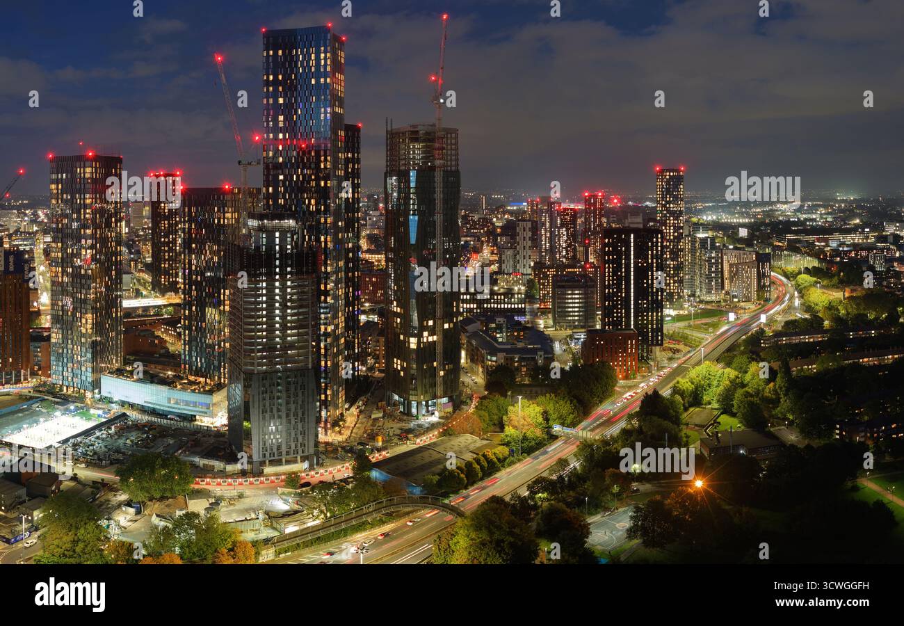 Immagine aerea al crepuscolo dello skyline di Manchester con grattacieli illuminati e la via mancuniana sottostante. Foto Stock