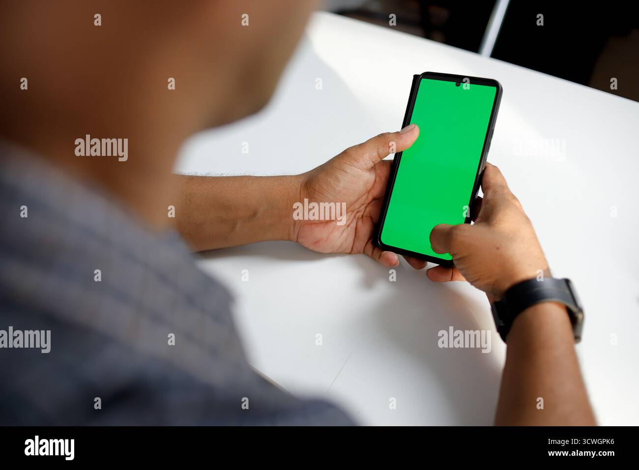 Uomo colpito ritagliato che usa un telefono cellulare mockup con montaggio su schermo verde. Foto Stock