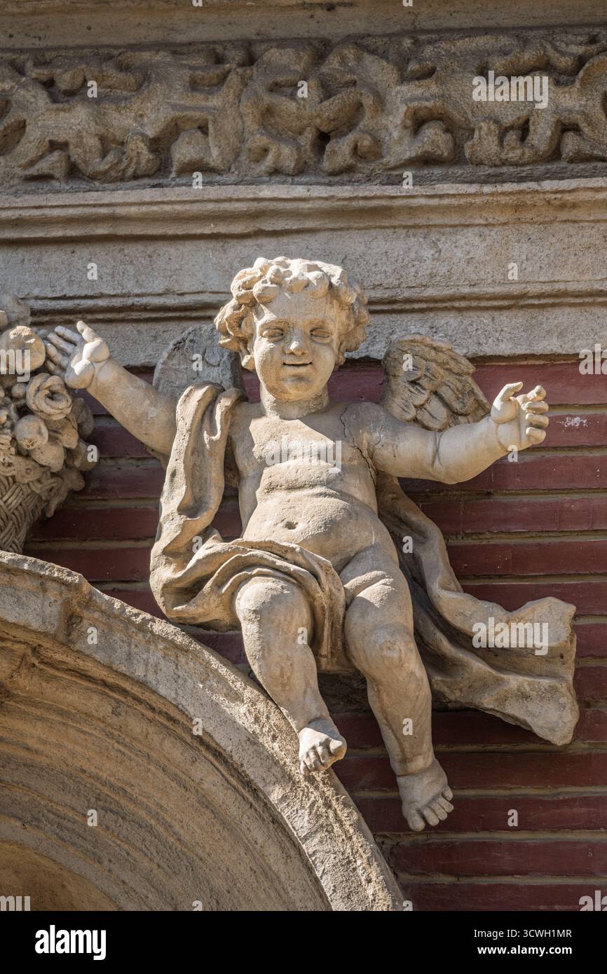 Un angelo barocco scolpito da Duque Cornejo mostra grazia e movimento con braccia allungate e tendaggi vorticosi sulla facciata di San Luis a Siviglia. Foto Stock