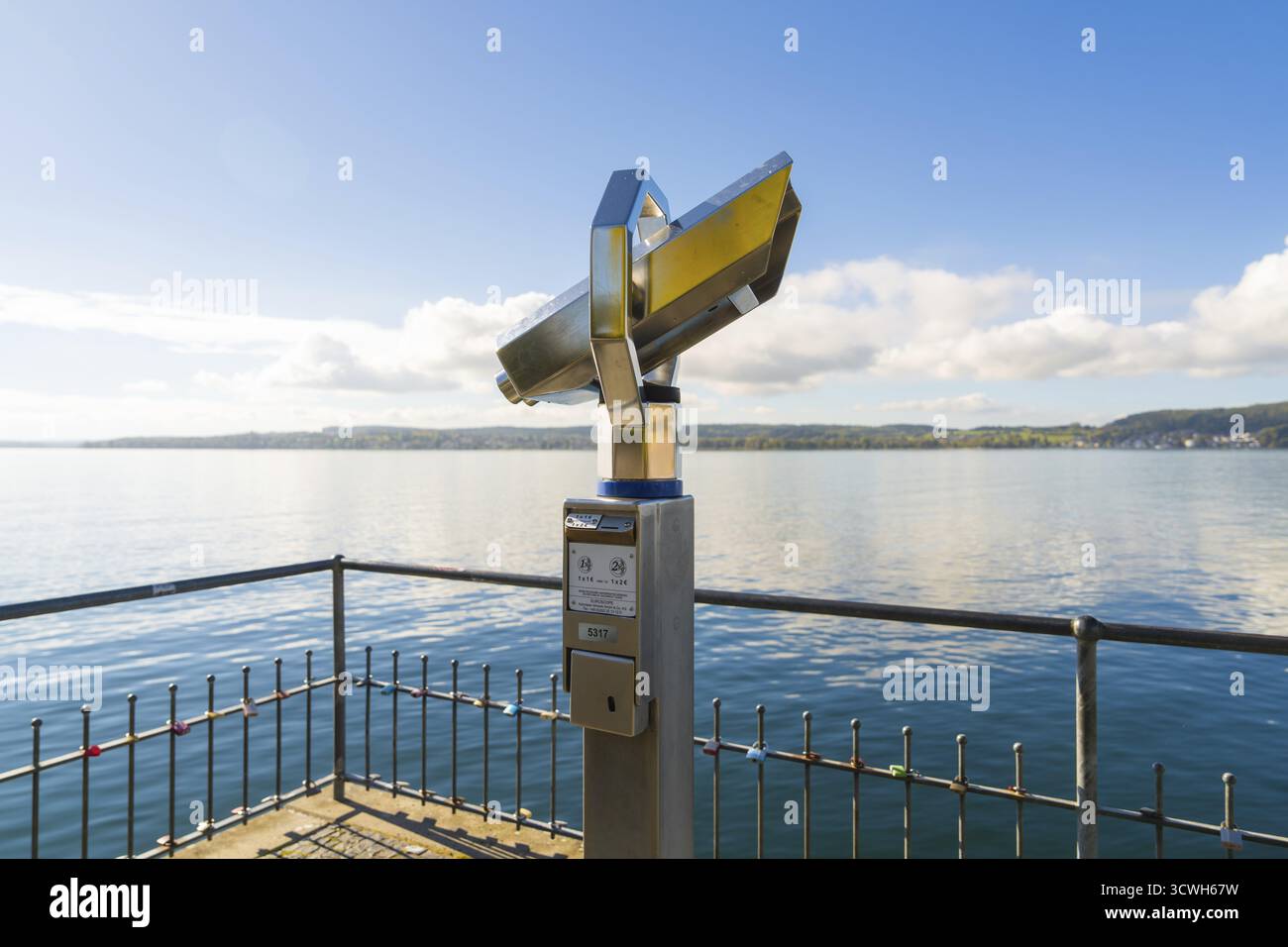 Binocolo sulla riva che indica un lago tranquillo con cielo blu e nuvole, Ueberlingen, lago di Costanza, Germania Foto Stock