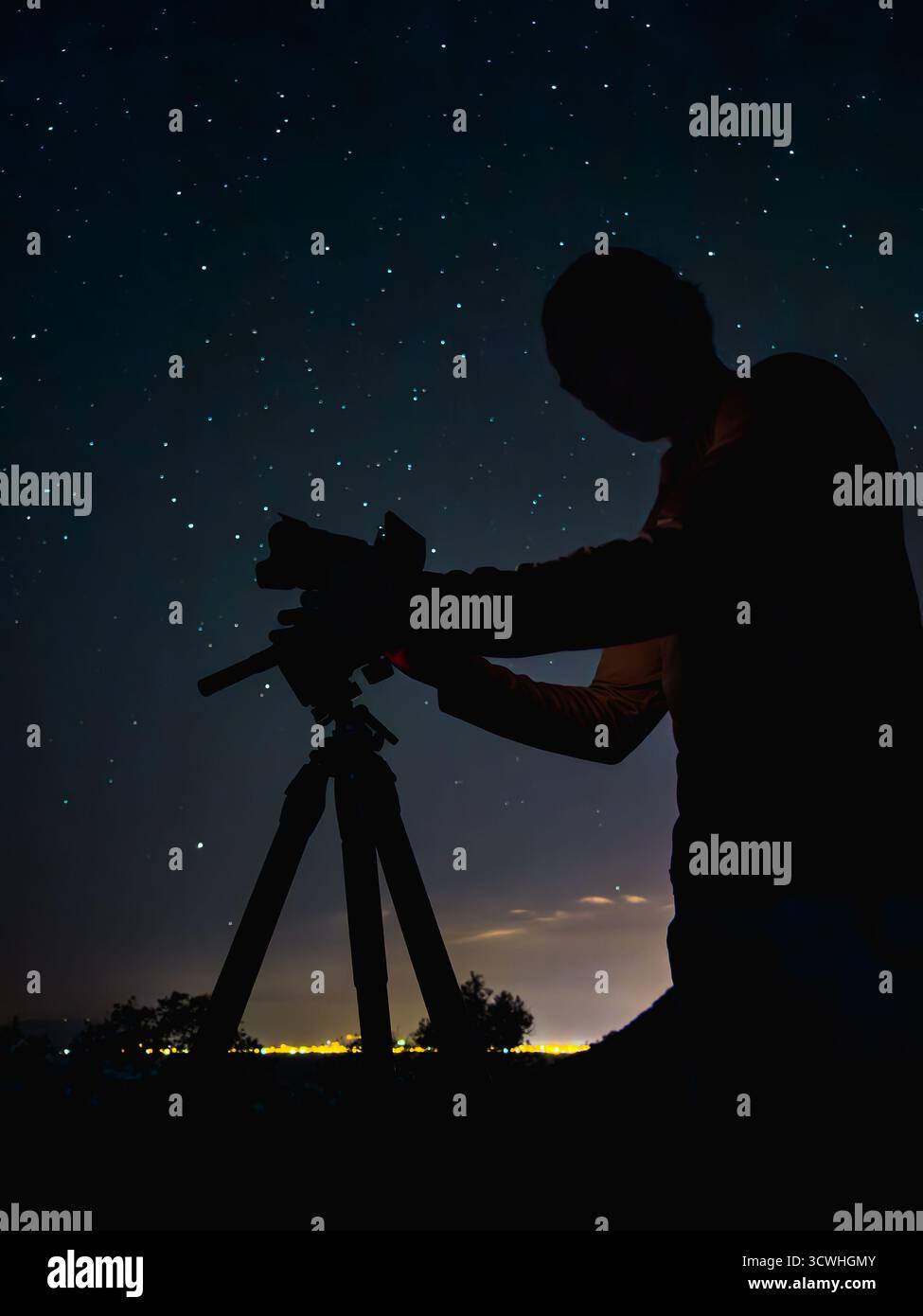 Silhouette di un fotografo che fotografa le stelle di notte sotto il cielo limpido Foto Stock