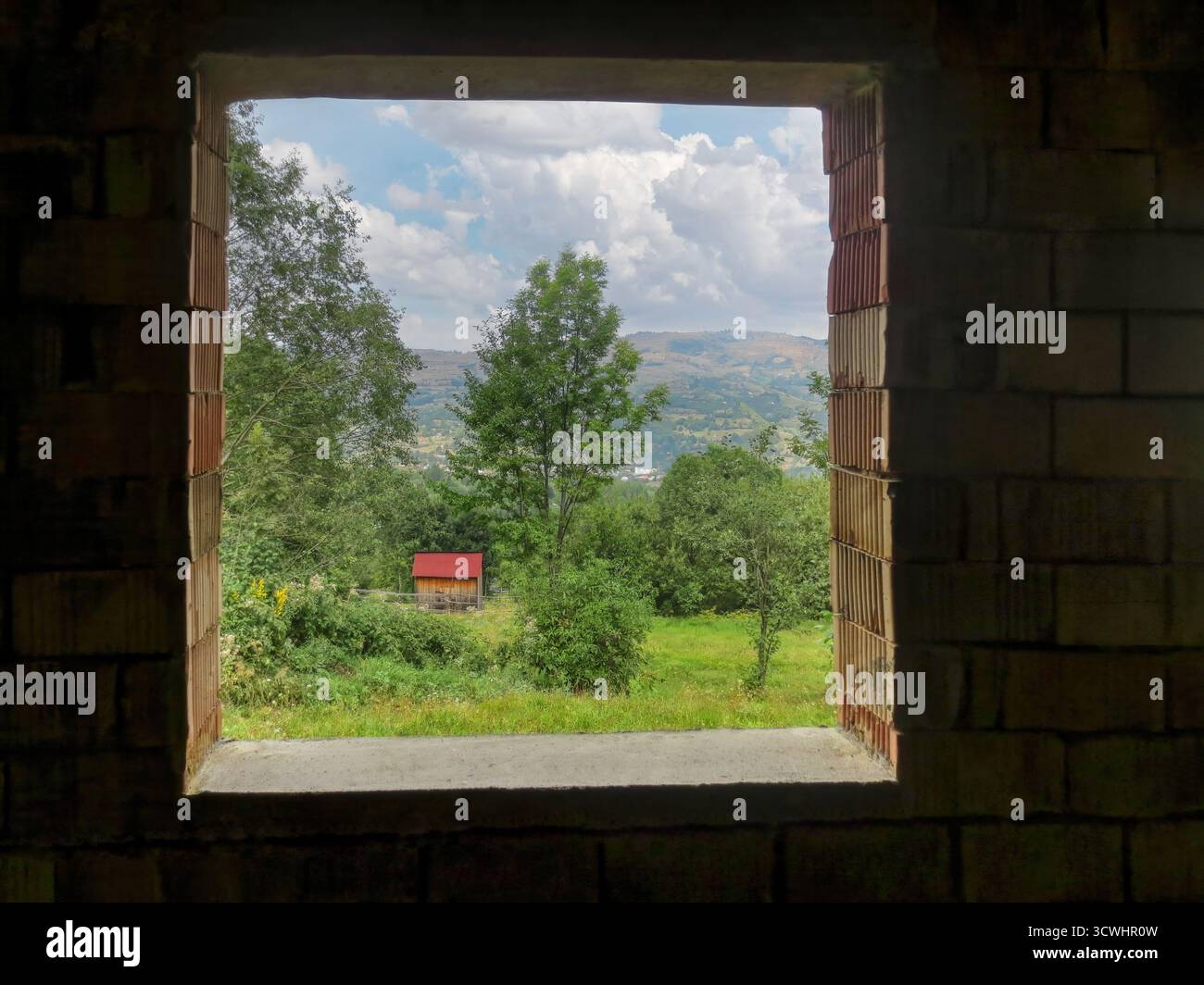 Vista dalla casa incompiuta con finestre, tradizionali case in legno con tetto a tegole in Transilvania, alberi, paesaggio sulle montagne della Romania, Foto Stock