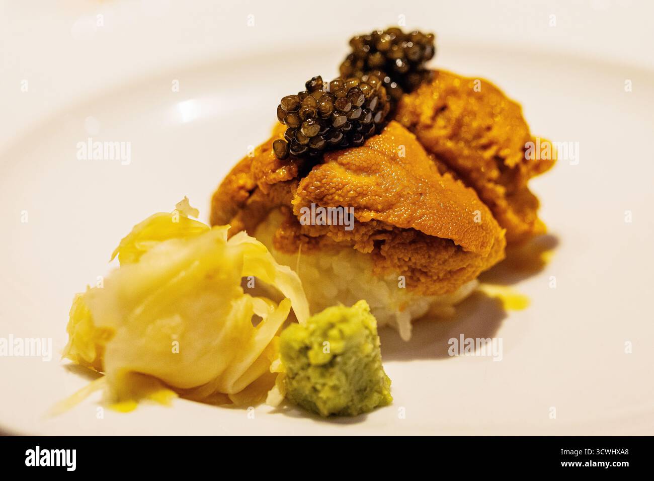 Il piatto di sushi gourmet presenta ricci di mare freschi conditi con caviale, accompagnati da wasabi e verdure sottaceto, mettendo in risalto l'arte culinaria. Foto Stock