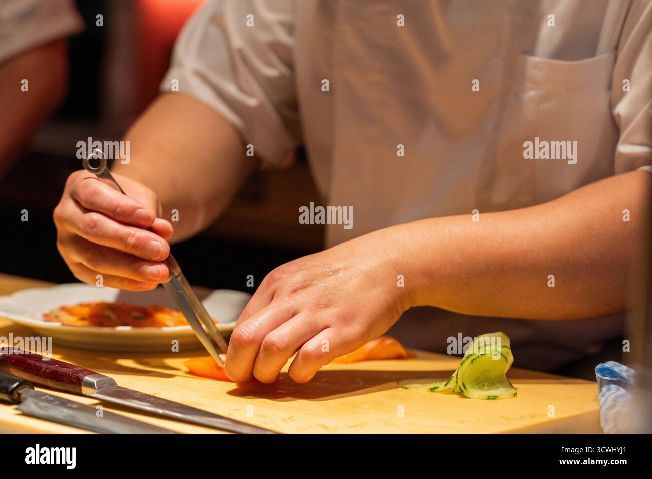 Lo chef esperto prepara sushi con ingredienti freschi su un ripiano in legno, mostrando esperienza culinaria e attenzione ai dettagli. Foto Stock