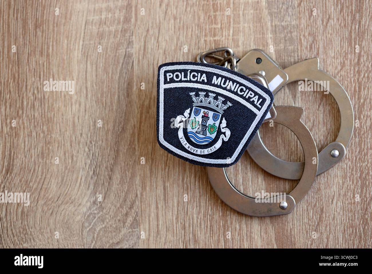 KIEV, UCRAINA - 6 SETTEMBRE 2025 Portogallo patch della polizia municipale e vecchie manette di metallo sul tavolo da vicino Foto Stock