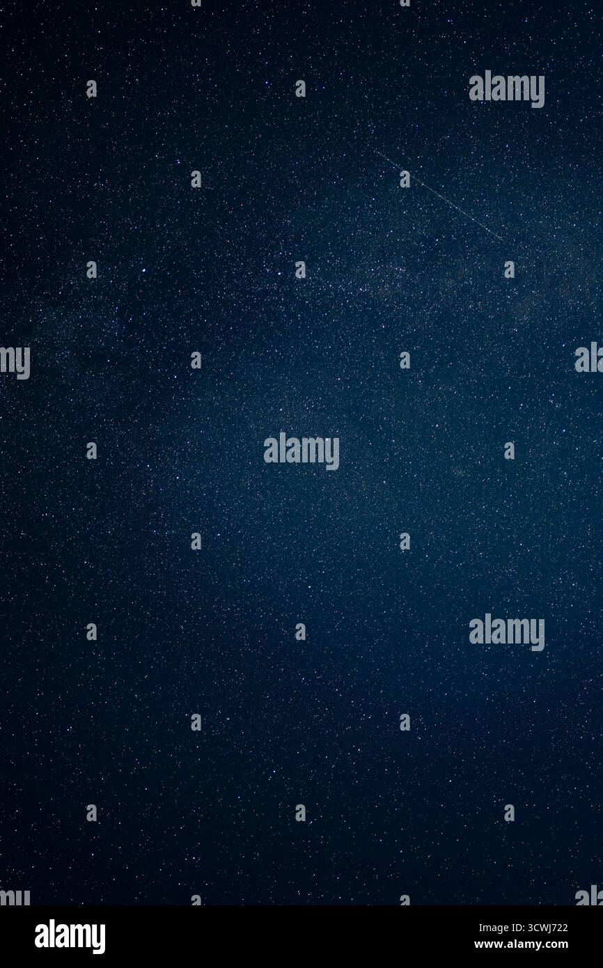 Un cielo notturno limpido in Islanda mostra la banda nuvolosa della via Lattea e una striscia di meteore diagonalmente, ambientata contro un bac blu profondo e privo di inquinamento luminoso Foto Stock