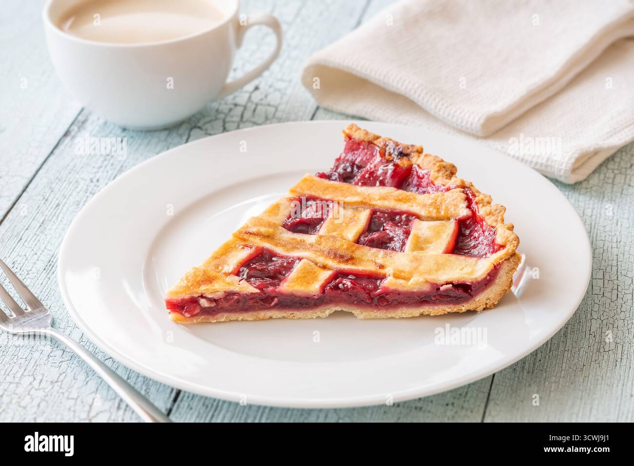 Crosta dorata e ripieno di rubino, accanto al caffè caldo, evocano un'intima indulgenza mattutina Foto Stock