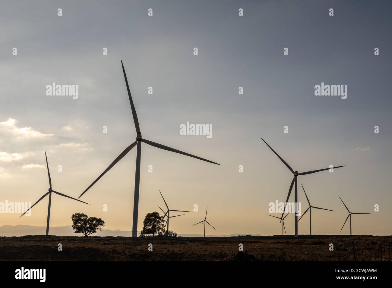Le turbine eoliche girano contro un vibrante tramonto sulle alture del Golan, generando energia pulita per Israele Foto Stock