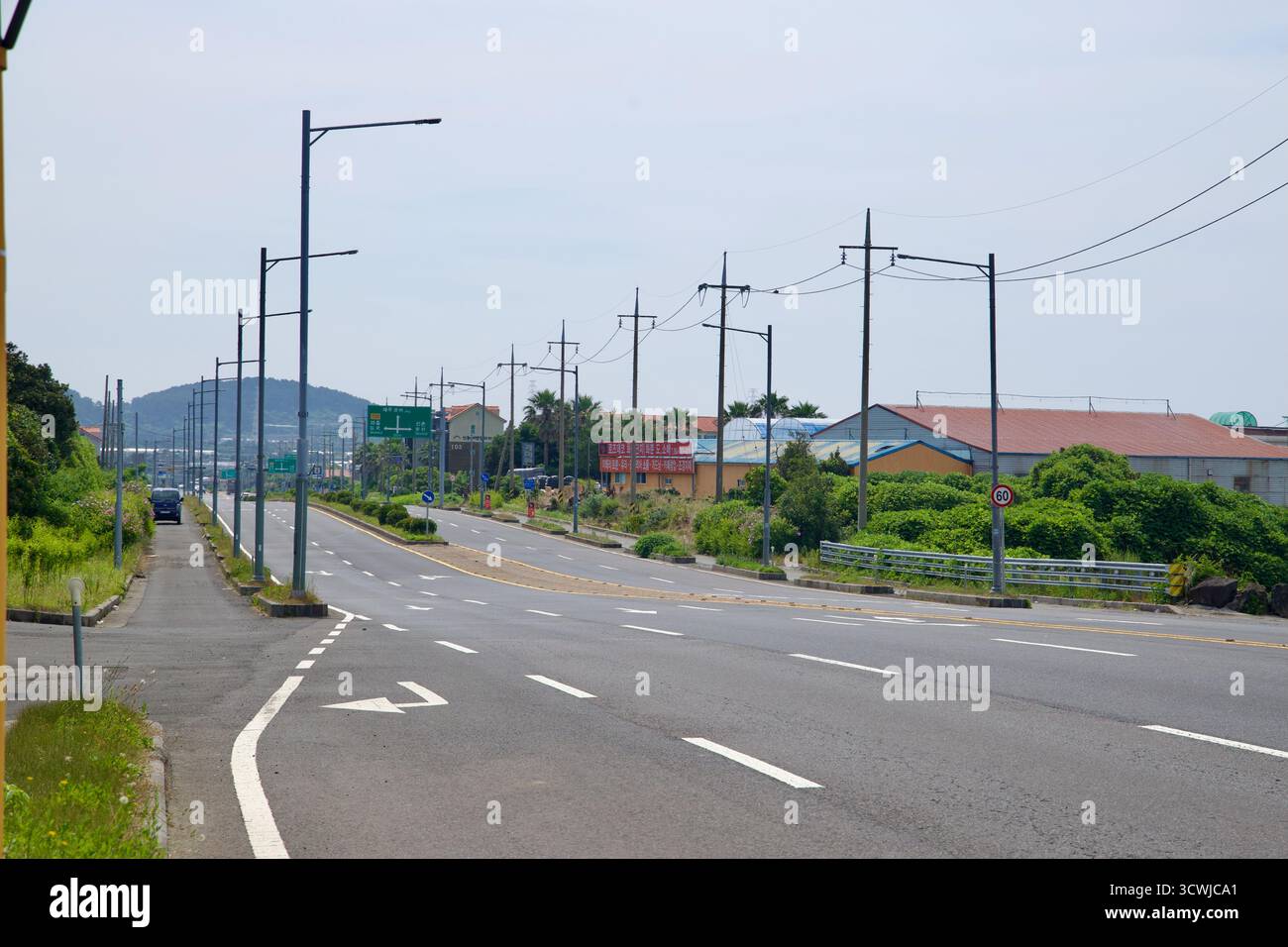 L'ampia vista di Iljudong-ro vicino a Samyang mostra più corsie di traffico, piantagioni mediane e pali di servizio che conducono verso basse colline, con lavori lungo la strada Foto Stock