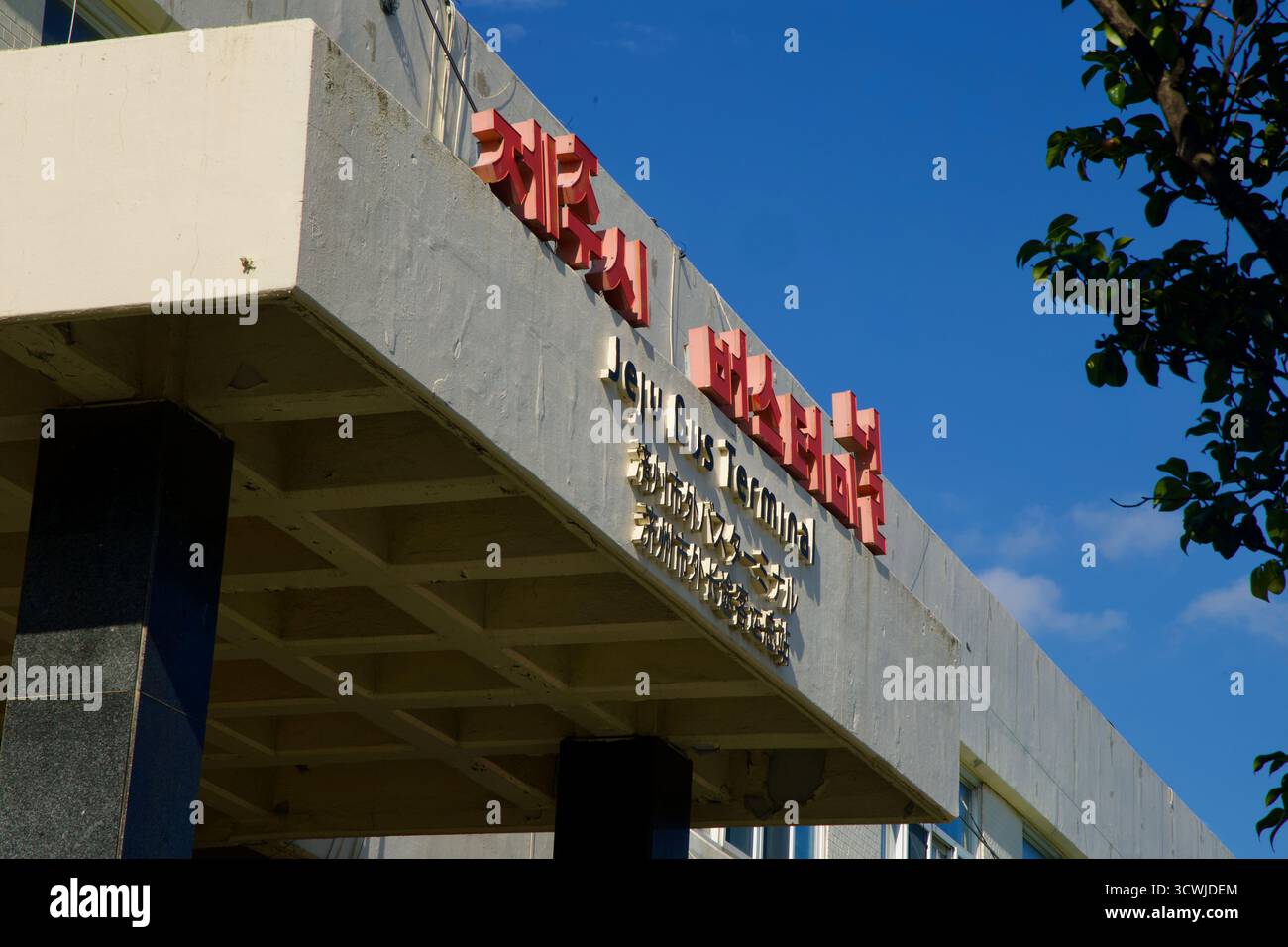 La scritta in rilievo per "Jeju Bus Terminal" in coreano, inglese, giapponese e cinese segna la copertura in cemento dell'edificio del terminal interurbano sottostante Foto Stock