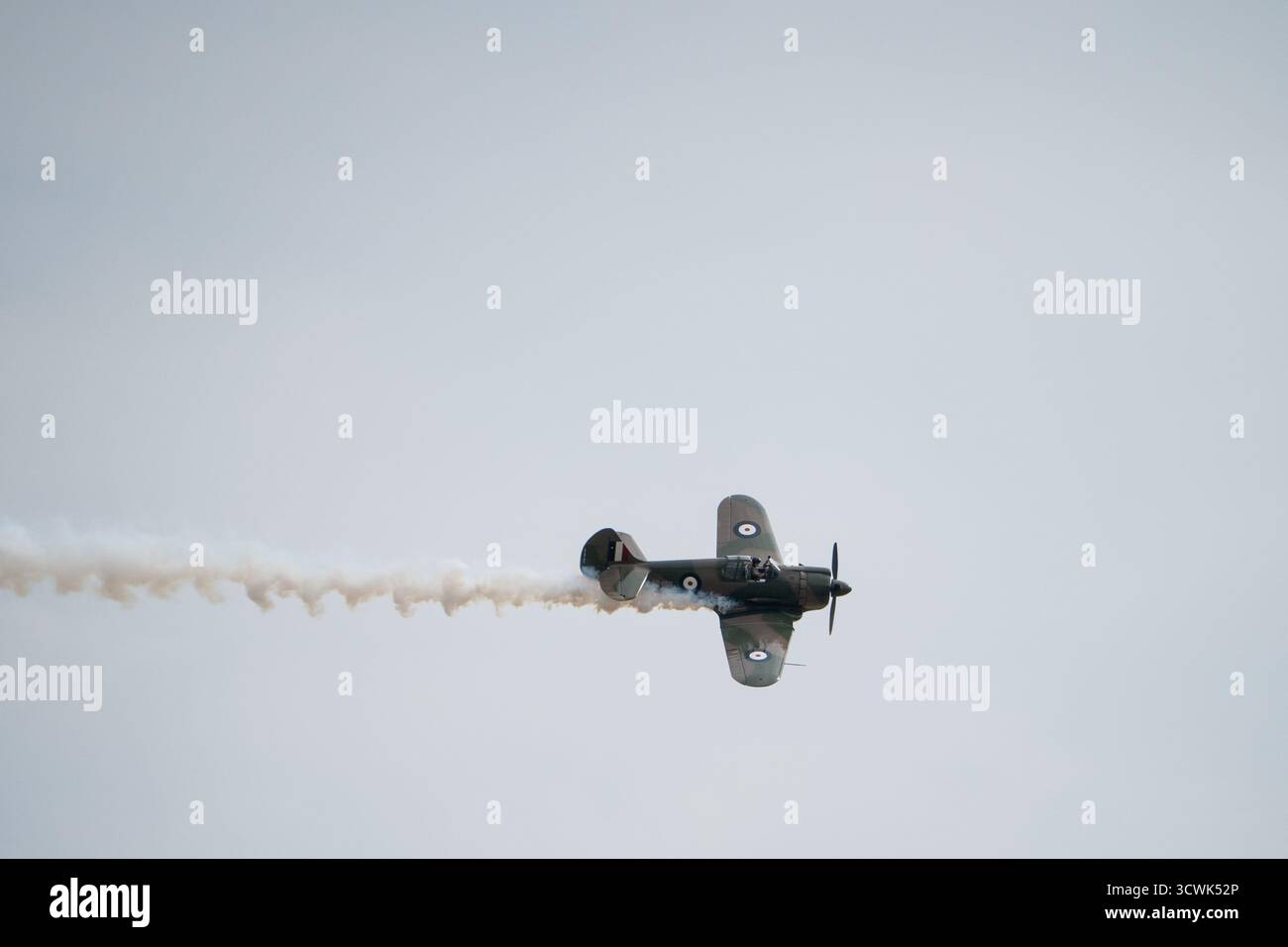 Velivoli da caccia vintage della RAF che eseguono esibizioni acrobatiche con tracce di fumo contro il cielo coperto Foto Stock