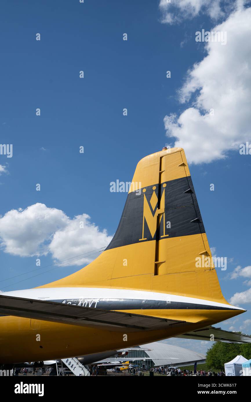 Pinna gialla e grigia della coda degli aerei contro il cielo blu con nuvole bianche a Duxford Foto Stock
