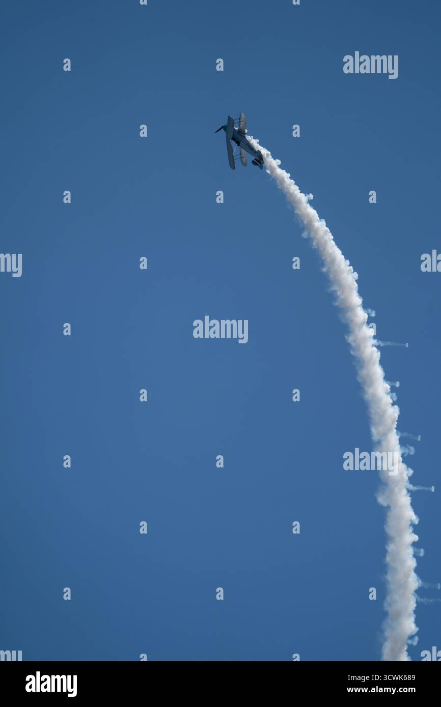 Velivoli acrobatici che eseguono arrampicate verticali con pista di fumo bianca contro il cielo azzurro Foto Stock