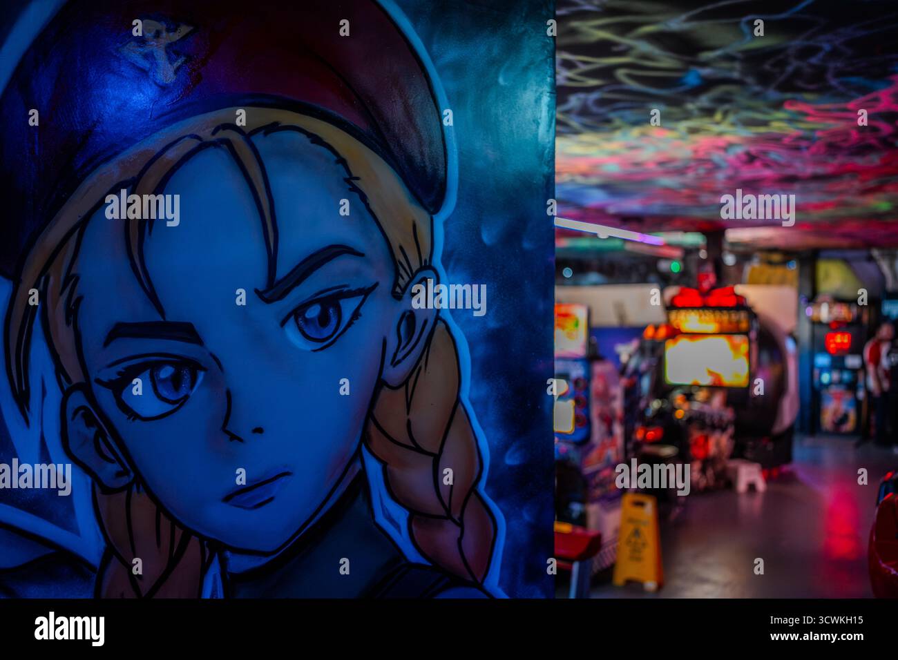 Un colorato murale di Cammy di Street Fighter decora la parete di un arcade retrò con macchine da gioco e luci al neon a Walsall, Regno Unito Foto Stock