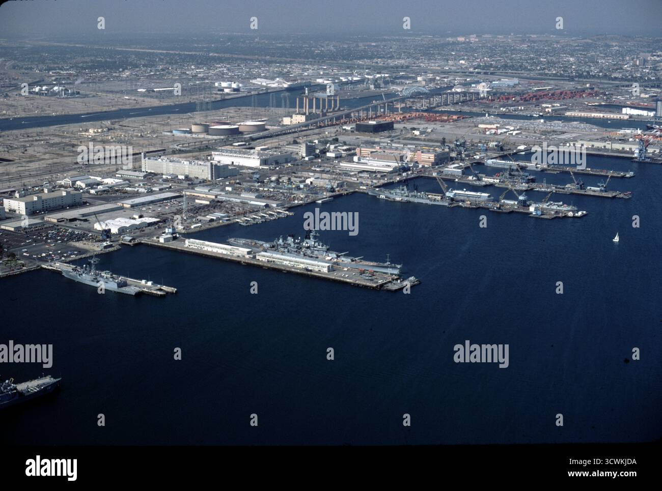 Long Beach CA USA 1984. La vista aerea della USS New Jersey (BB-62) è una nave da battaglia della classe Iowa, ed è stata la seconda nave della United States Navy a prendere il nome dallo stato statunitense del New Jersey. È stata spesso chiamata affettuosamente "Big J". Il New Jersey guadagnò più Battle Star per le azioni di combattimento rispetto alle altre tre navi da battaglia completate della classe Iowa, e fu l'unica nave da battaglia statunitense utilizzata per fornire supporto al fuoco durante la guerra del Vietnam. Foto Stock