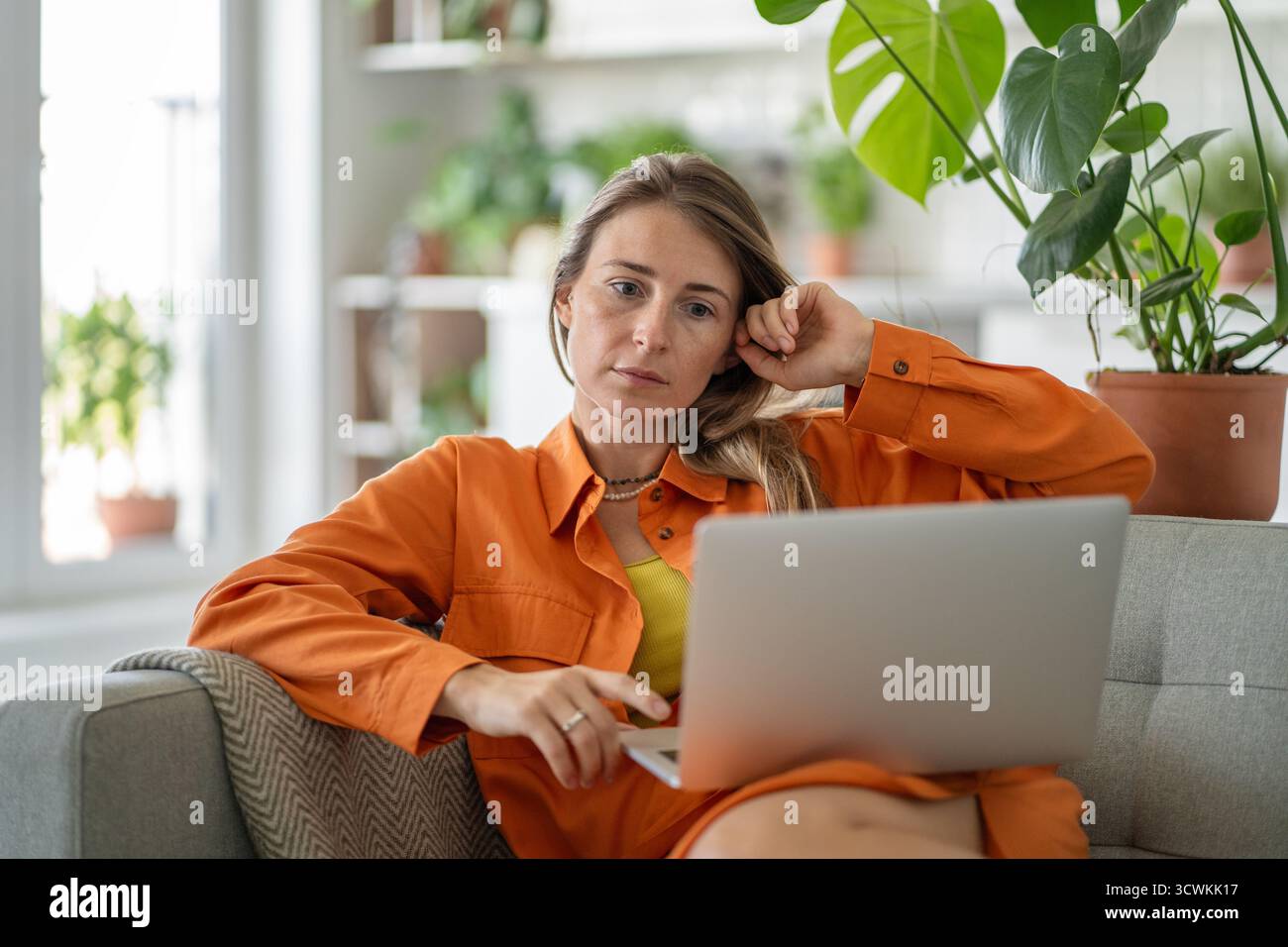 Donna di mezza età impegnata nella comunicazione online tramite notebook che esprime intensamente focalizzata e tesa Foto Stock