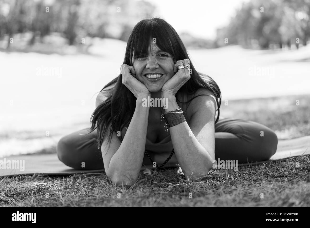 Donna sorridente mentre riposa in una comoda posa yoga a terra. Foto Stock