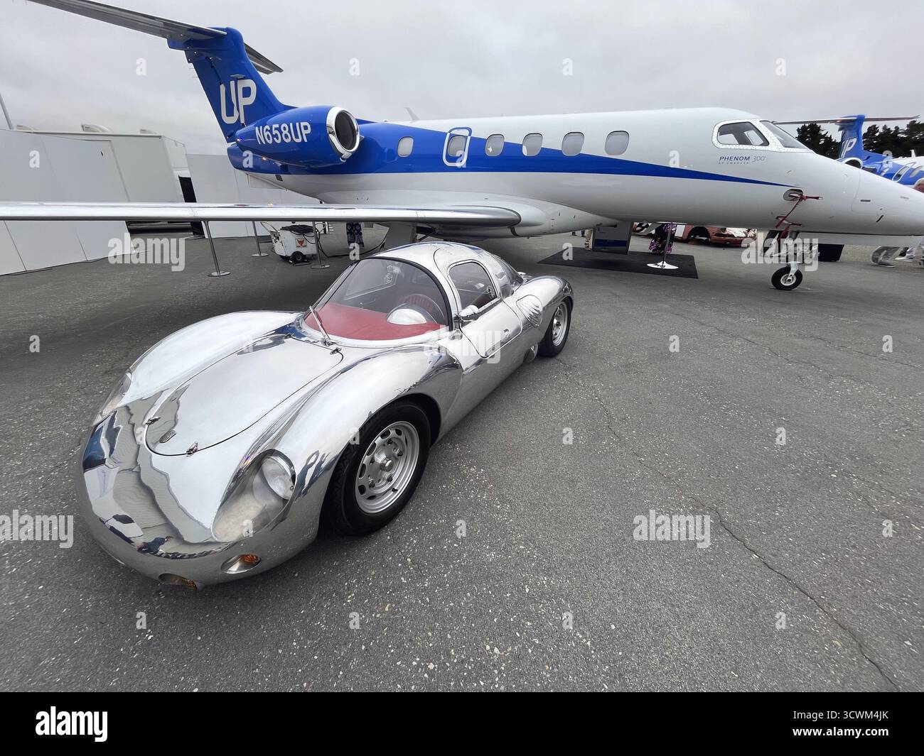 Monterey, CALIFORNIA, USA, 13 agosto 2025 – un'auto sportiva e un jet di lusso in argento sono esposti all'evento Motorlux. La Classic Car Week è un evento annuale. Foto Stock