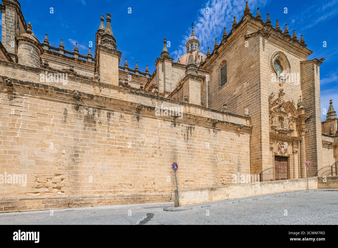 Il fianco sud-ovest della cattedrale di Jerez mostra intricati lavori in pietra, con merlature e rosone sopra il portale secondario di Cadice. Foto Stock