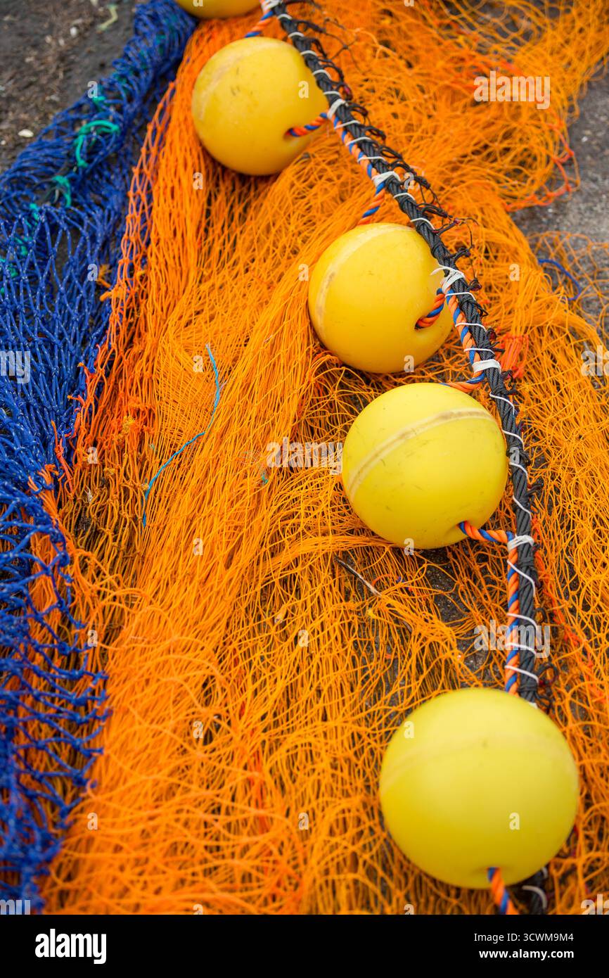 Rete a strascico dai colori vivaci con galleggianti a fune. I galleggianti sferici gialli vibranti sono disposti lungo una corda spessa, intrecciata con arancione e blu Foto Stock