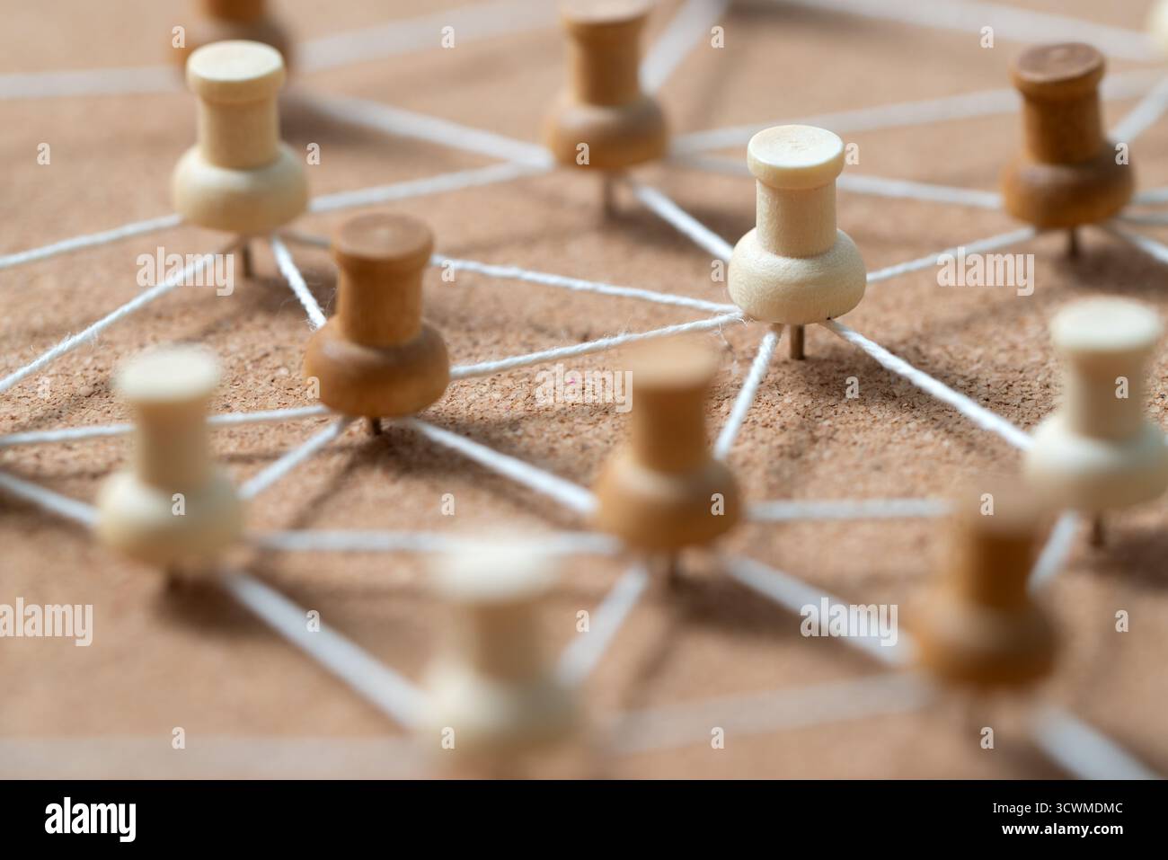 Pulsanti in legno collegati da una corda bianca su un cordoncino, che illustrano un social network, un collegamento tra persone o una mappa concettuale. Foto Stock