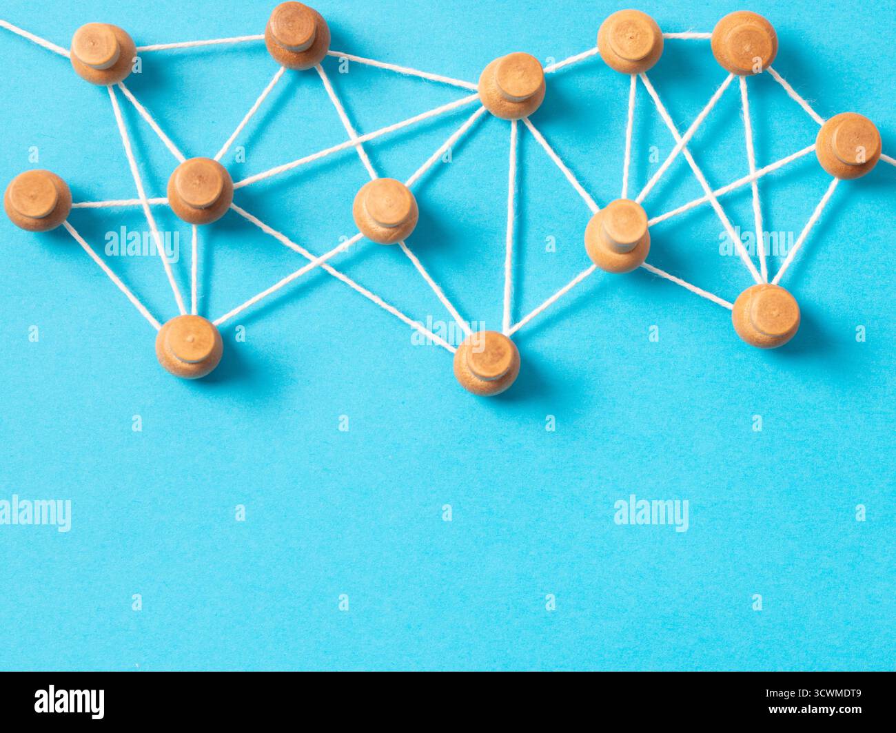 Pulsanti o miniature in legno collegati da una stringa bianca su sfondo blu, che illustrano una rete di social media, una connessione tra persone o una mappa concettuale. Foto Stock