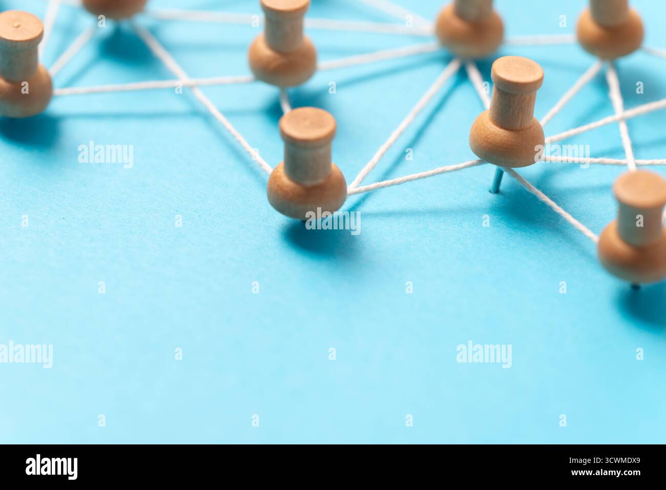 Pulsanti o miniature in legno collegati da una stringa bianca su sfondo blu, che illustrano una rete di social media, una connessione tra persone o una mappa concettuale. Foto Stock