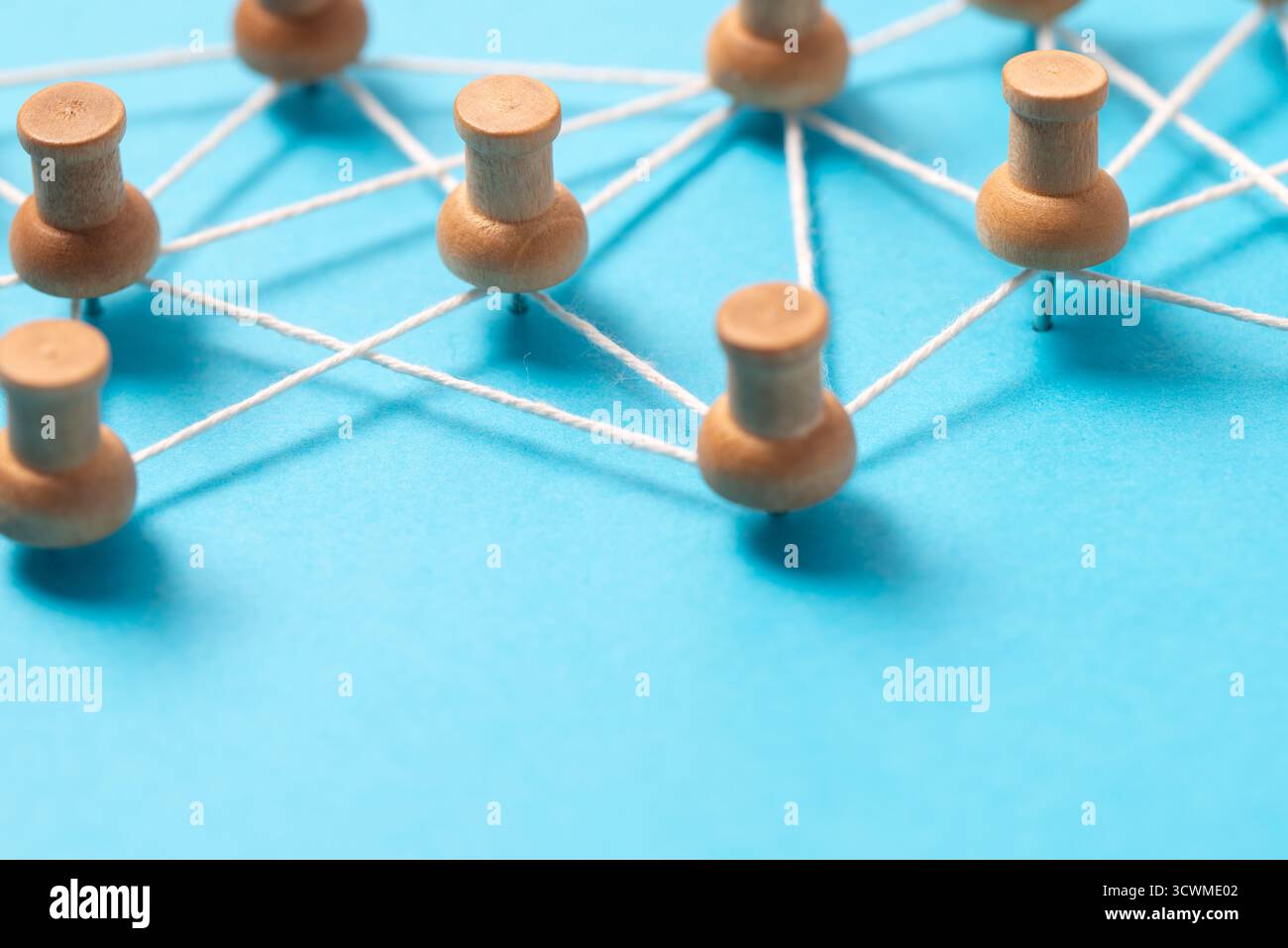 Pulsanti o miniature in legno collegati da una stringa bianca su sfondo blu, che illustrano una rete di social media, una connessione tra persone o una mappa concettuale. Foto Stock