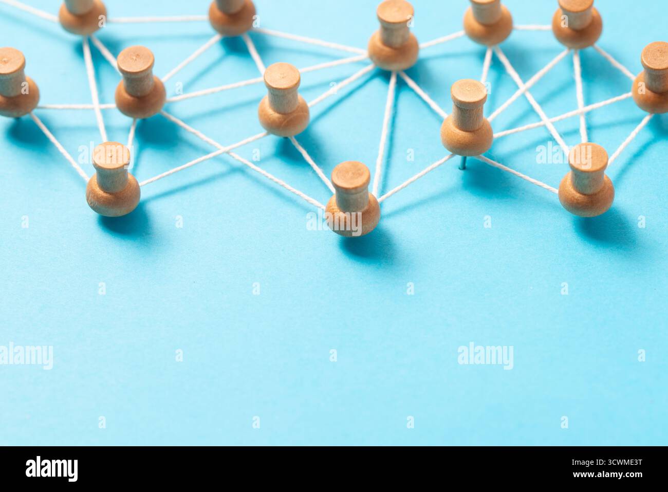 Pulsanti o miniature in legno collegati da una stringa bianca su sfondo blu, che illustrano una rete di social media, una connessione tra persone o una mappa concettuale. Foto Stock