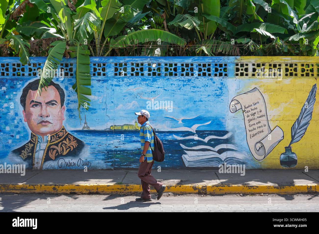 Altagracia, Nicaragua - 8 ottobre 2025: Un uomo che cammina lungo una strada con un murale di Ruben Dario sullo sfondo ad Altagracia sull'isola di Ometepe. Foto Stock